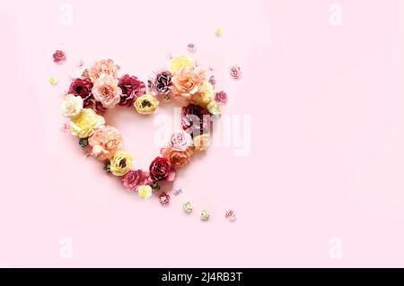Happy mother's and Valentines day. Bouquet of colorful assorted roses in heart shape on pink background and butterfly. Holiday concept Stock Photo