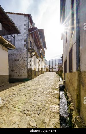 Narrow alley of old houses with water channel that goes down the street from the mountain, Candelario Salamanca. Stock Photo
