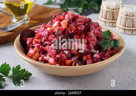 Traditional Salad Vinaigrette with beans, pickles, pickled cabbage and boiled vegetables in a clay plate on gray background, Vegetarian food Stock Photo