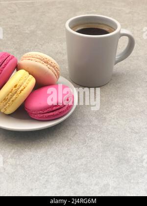 macaroons, colorful delicious and beautiful macaroons and cup of coffee on gray table or background or surface with copy space. coffee and cookie conc Stock Photo