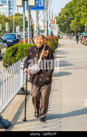 ANQING, CHINA - MARCH 21: Senior woman walks on street.  A 80 years old Chinese lady with a cane walks on the street on March 21, 2014. Stock Photo