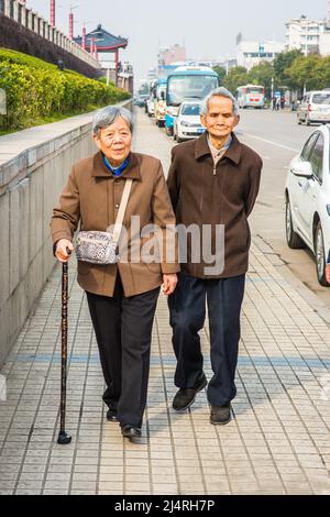 Senior Man and Woman Walking Outside. A  senior couple, 80 years old, is walking on street, woman holding a walking stick. Stock Photo