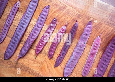 Purple Guaje seed pods arranged on a wood table Stock Photo