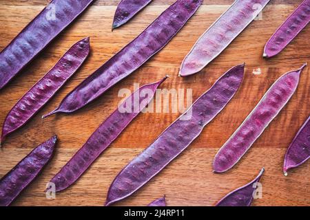 Purple Guaje seed pods arranged on a wood table Stock Photo