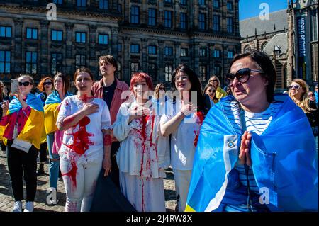 Amsterdam, Netherlands. 17th Apr, 2022. A group of Ukrainian women covered in fake blood sing the Ukrainian national anthem during the demonstration. The Ukrainian community in The Netherlands performed in the city center of Amsterdam a flashmob to highlight the devastating impact of the ongoing war in Ukraine. Protesters laid on the ground playing dead to protest the violence and rising death toll in Ukraine and to demand further sanctions on Russia. (Photo by Ana Fernandez/SOPA Images/Sipa USA) Credit: Sipa USA/Alamy Live News Stock Photo