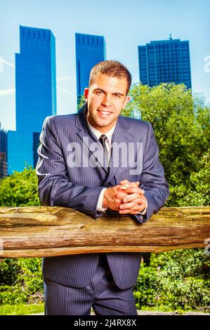 Portrait of young businessman. Dressing formally in a blue suit, black tie, a young professional guy is standing in the front of business district, sm Stock Photo
