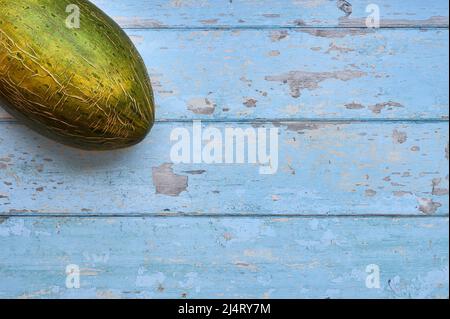 detail of an unbroken melon on a wooden background with blue slats Stock Photo