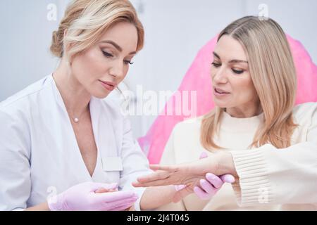 Concentrated professional dermatologist performing cutaneous examination procedure Stock Photo