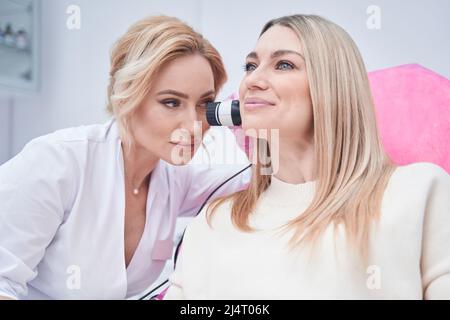 Dermatologist using dermoscopy equipment on client skin Stock Photo