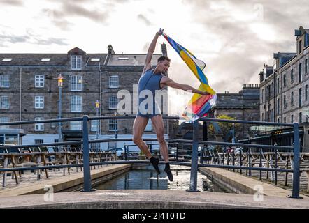 Scottish Ballet principal dancer Jerome Anthony Barnes leaps into the air with Edinburgh International Festival 75th anniversary flag, Leith, Scotland Stock Photo