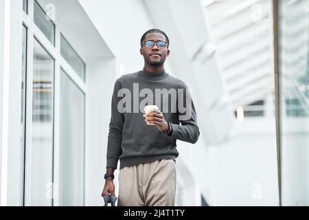 Minimal portrait of young black businessman walking towards camera in office building while starting work in morning, copy space Stock Photo