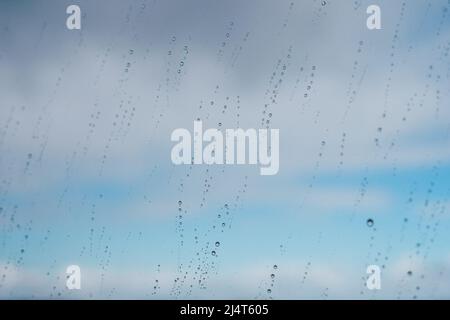 Raindrops on a window against the blue sky with clouds Stock Photo
