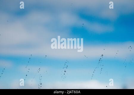 Raindrops on a window against the blue sky with clouds Stock Photo