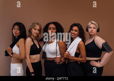 Group portrait of a five women in sportswear standing together on brown background Stock Photo