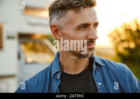 Grey european man smiling and looking away while standing outdoors Stock Photo