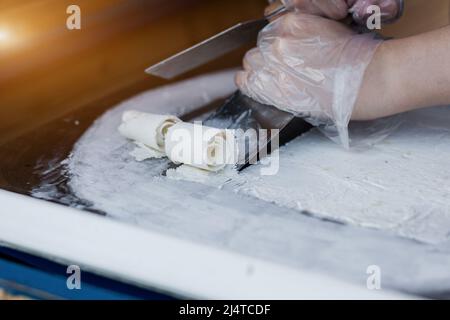 Thai roll ice cream is made by hand on the freezer. Sweet dessert made from natural and ingredients. The process of making food. Stock Photo