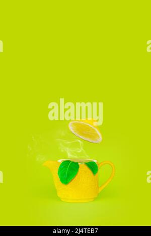 Teapot in lemon form with steam, leaf lemon on green background. English tea time concept. Brewing and Drinking tea.Lemon kettle teapot with steam and Stock Photo