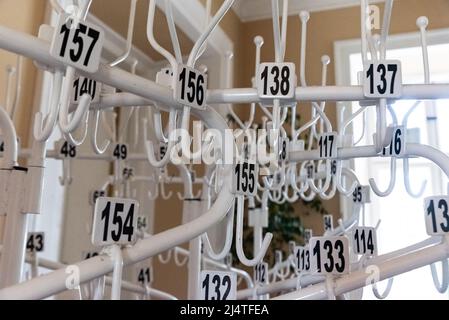 A clothes hanger in the hotel cloakroom. Multiple numbered hangers on multiple plans with a blurred background. Stock Photo