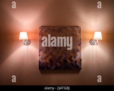 Locarno, Switzerland - December 12, 2021: An abstract work of art on the wall surrounded by two lit lamps Stock Photo