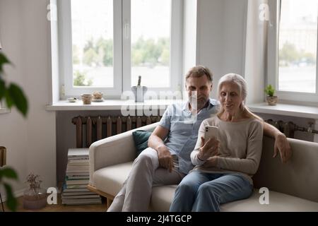 Mature couple staring at smartphone having video call remote conversation Stock Photo