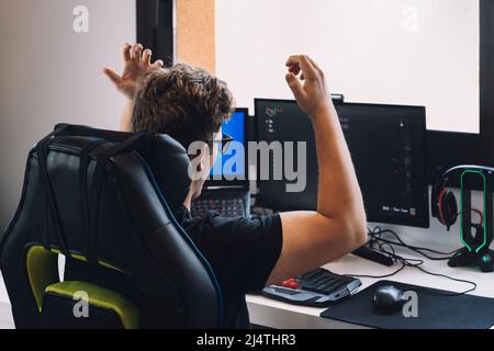 young blond man happily celebrating winning a video game on his computer. Stock Photo