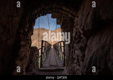 Dark Tunnel Walls Open Up To The Black Bridge Over The Colorado River in the Grand Canyon Stock Photo