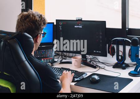 young blond man working sitting in his desk chair at home at his computer. Stock Photo