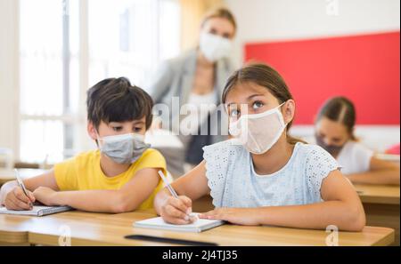 Kid in mask cheating during test Stock Photo