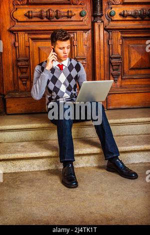 Man Working Hard. Wearing a patterned sweater, red tie, blue jeans, leather shoes, a young guy is sitting on stairs in the front office door, talking Stock Photo