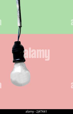 Single hanging white light bulb on black fixture with pink and green background.Copy space for title, text. Stock Photo
