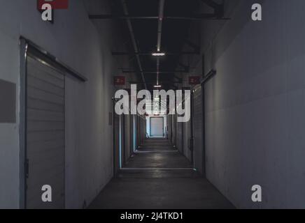 Long dark corridor with doors to storage in a warehouse Stock Photo