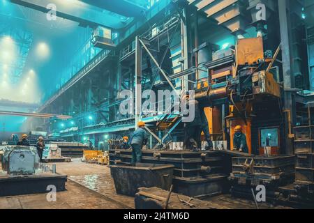 Steel mill interior inside. Workers in workshop of metallurgical plant. Foundry and heavy industry building inside background.