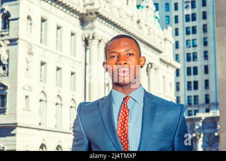 Portrait of Black Businessman. Dressing formally in blue suit, patterned undershirt, tie, short haircut, a young handsome black guy is standing in a b Stock Photo