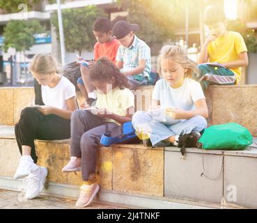 Preteen classmates preparing schoolwork outside school Stock Photo