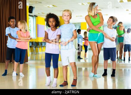 Group of preteen children training movements of slow foxtrot in dance ...