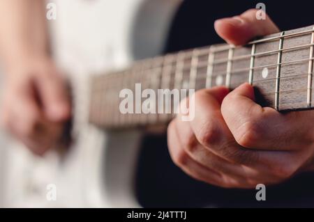 close up caucasian male hand playing white electric guitar making a chord, focus on left hand, music concept, copy space Stock Photo