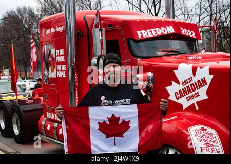 A truck driver part of the Great Canadian Cruise holds a flag at an event to protest the country's vaccine mandates and other COVID restrictions. Stock Photo