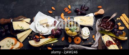 Cheese board on dark background. Celebration gathering. Food for wine, snacks, delicatessen. panorama, copy space, flat lay Stock Photo