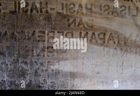 Dirty grunge fabric with lettering on concrete wall in Bali, Indonesia Stock Photo