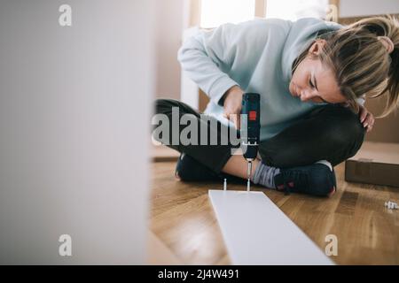 Woman using screwdriver for assembling furniture at home Stock Photo