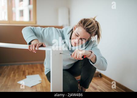 Woman using screwdriver for assembling furniture at home Stock Photo