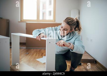 Woman using screwdriver for assembling furniture at home Stock Photo