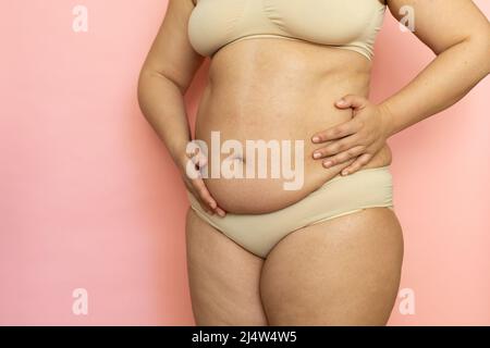 Premium Photo  Touch woman sagging belly closeup folds on tummy loose skin  and cellulite obesity naked overweight plus size girl on pink background in  beige underwear concept of dieting and body