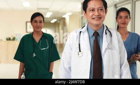 Group of medics busy with clipboard discussing along hospital corridor, Doctor and nurse team with medical report walking down hallway at the hospital Stock Photo