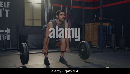 Muscular young Caucasian man exercises working out with lifting weights heavy barbell, Male bodybuilder having workout in gym and fitness club during Stock Photo