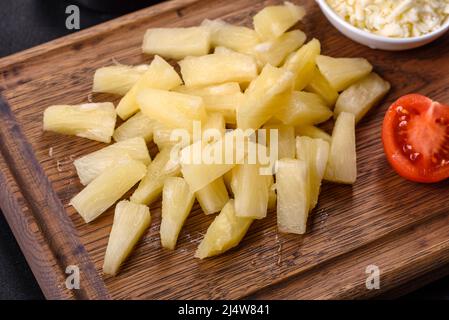 Canned pineapple chunks. Pineapple pieces on dark background Stock Photo