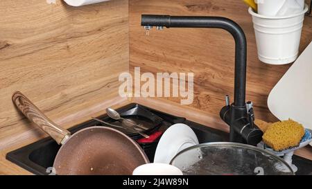 Heap of dirty dishes in sink and broken faucet leaking Stock Photo