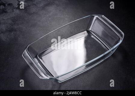 A rectangular glass empty dish for baking on a dark concrete background. Preparation for baking tasty cupcake Stock Photo