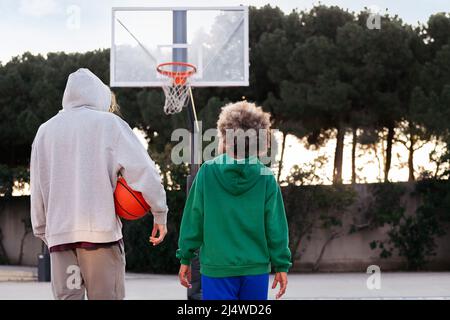 rear view of two friends walking on the basketball court after a game, concept of friendship and urban sport in the street, copy space for text Stock Photo