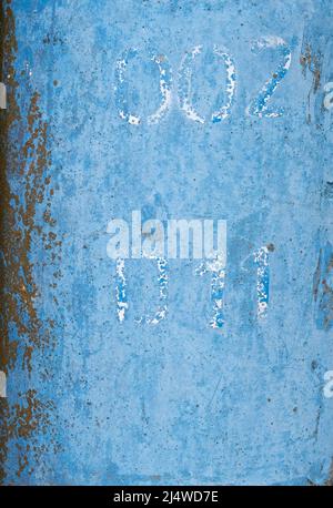 Close up view of faded blue painted sign with numbers on metal pole in street Stock Photo